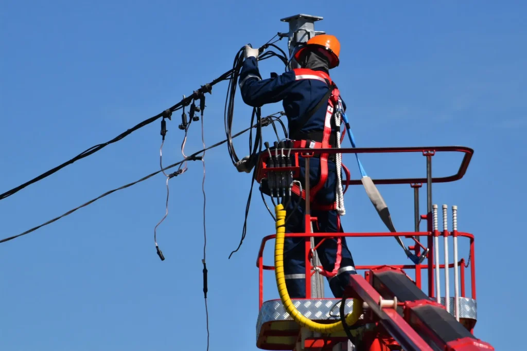 Man in rood en zwart die onderhoud pleegt aan het elektriciteitsnetwerk